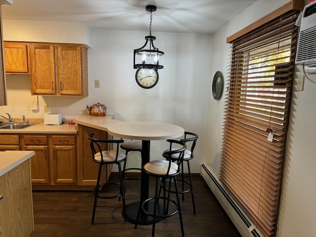 kitchen with sink, hanging light fixtures, an inviting chandelier, dark hardwood / wood-style flooring, and a baseboard heating unit