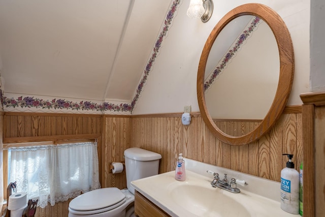 bathroom with vanity, wooden walls, and toilet