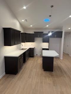 kitchen with decorative light fixtures, light wood-type flooring, a center island, and sink