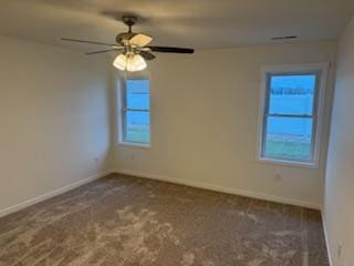 empty room featuring dark carpet and ceiling fan