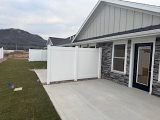 view of property exterior featuring a patio area, a mountain view, and a yard