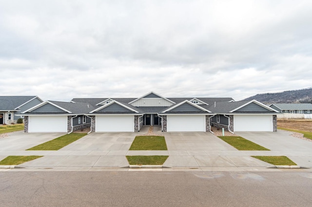 ranch-style house featuring a garage, driveway, board and batten siding, and stone siding