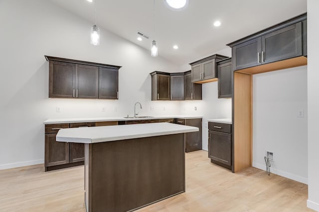 kitchen featuring a kitchen island, lofted ceiling, a sink, and light wood-style flooring