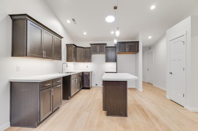 kitchen with a center island, light wood finished floors, visible vents, dark brown cabinetry, and a sink