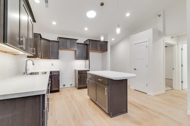 kitchen featuring light wood-style flooring, dark brown cabinetry, a kitchen island, a sink, and visible vents