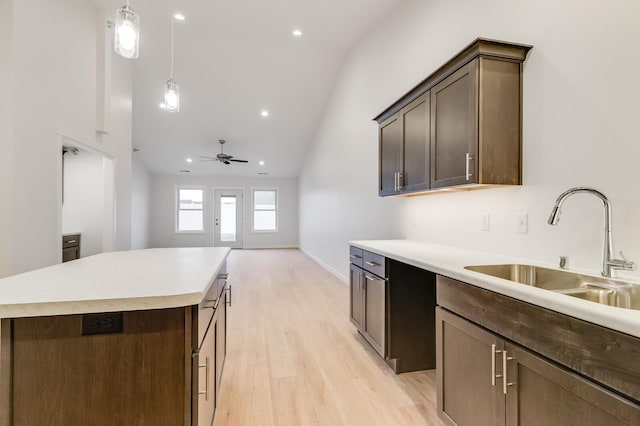 kitchen with ceiling fan, a sink, dark brown cabinets, light countertops, and light wood finished floors