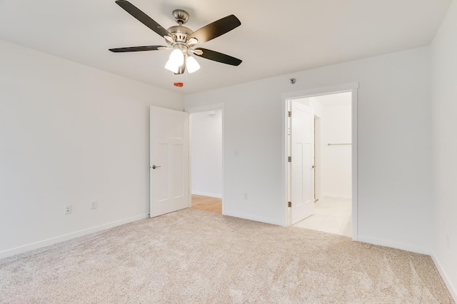 unfurnished bedroom featuring light carpet, ceiling fan, baseboards, and ensuite bathroom