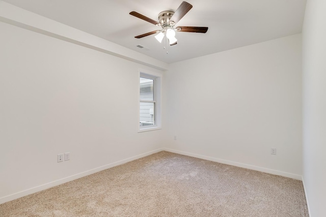 spare room featuring baseboards, a ceiling fan, visible vents, and light colored carpet