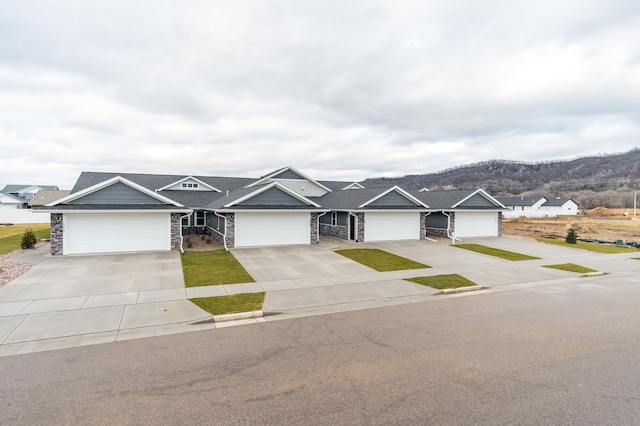 single story home with driveway, stone siding, and a mountain view