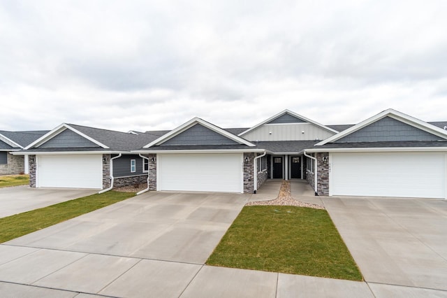 ranch-style home featuring a garage, concrete driveway, a shingled roof, and stone siding