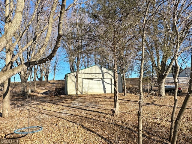 view of yard with a detached garage, fence, and an outbuilding