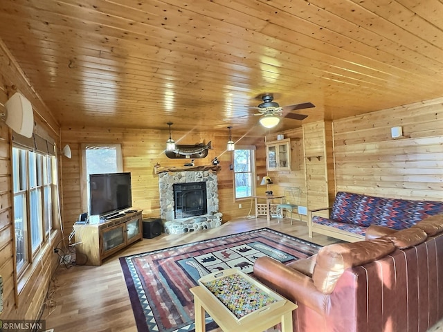 living area featuring wooden ceiling, a fireplace, ceiling fan, wooden walls, and wood finished floors