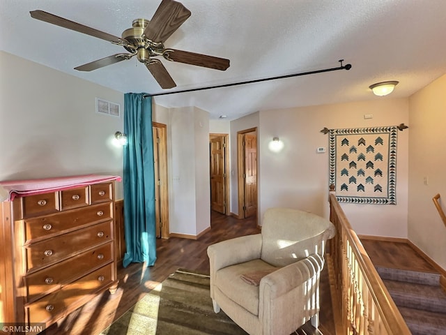 living area featuring an upstairs landing, dark wood-type flooring, a ceiling fan, visible vents, and baseboards