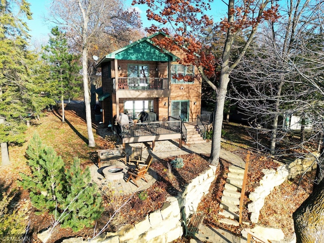 rear view of house featuring stairs, a balcony, and a wooden deck