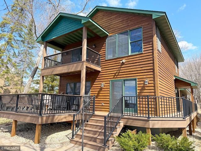 back of property with a wooden deck and a balcony