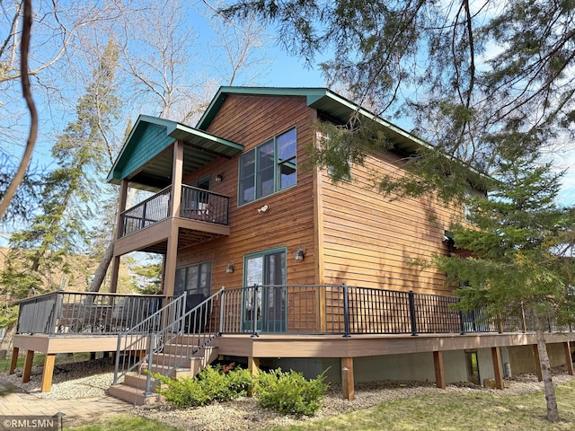rear view of house featuring a wooden deck and a balcony