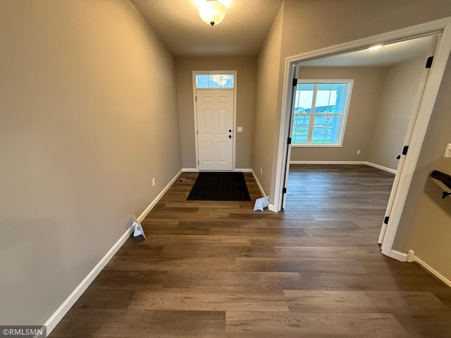 doorway with a textured ceiling and dark hardwood / wood-style floors