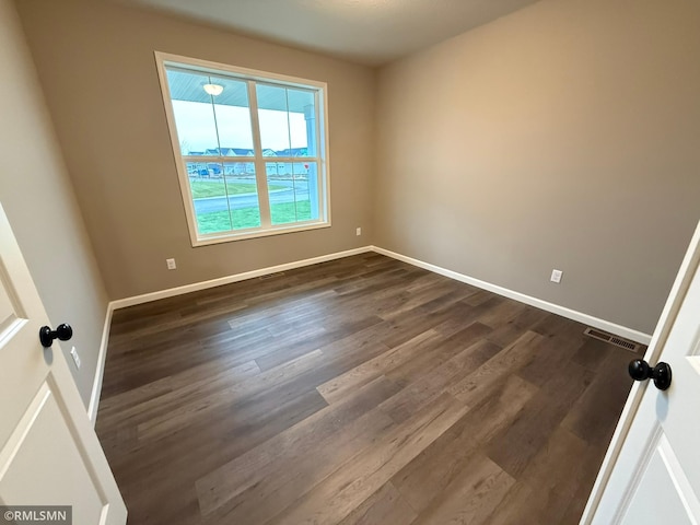 unfurnished room with dark wood-type flooring