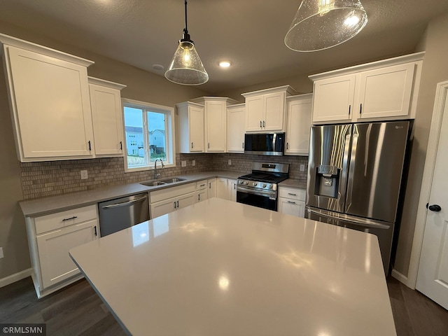 kitchen featuring decorative light fixtures, stainless steel appliances, white cabinetry, and sink