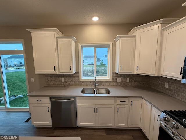 kitchen with decorative backsplash, dark hardwood / wood-style flooring, stainless steel appliances, sink, and white cabinets