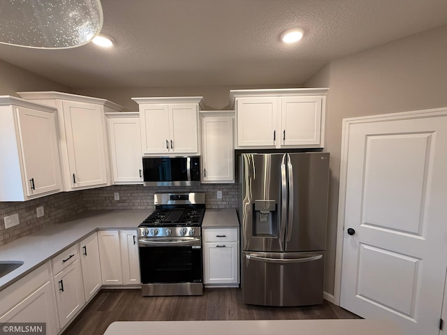 kitchen with stainless steel appliances, tasteful backsplash, dark hardwood / wood-style floors, a textured ceiling, and white cabinets