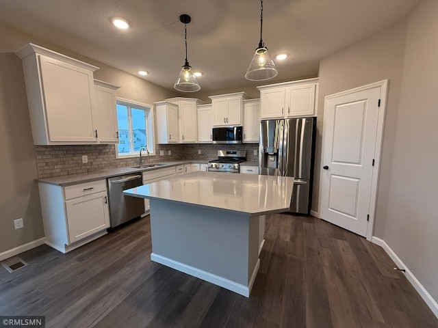 kitchen with white cabinets, dark hardwood / wood-style floors, pendant lighting, and stainless steel appliances