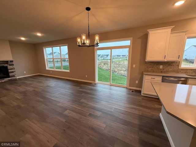 unfurnished dining area with a fireplace, dark hardwood / wood-style flooring, and an inviting chandelier