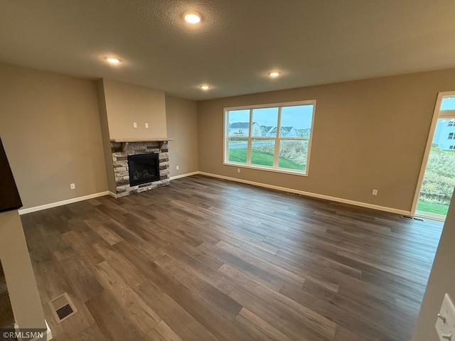 unfurnished living room with a fireplace, a textured ceiling, and dark wood-type flooring