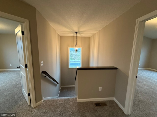 stairway featuring carpet flooring, a chandelier, and a textured ceiling