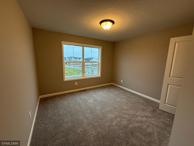 carpeted empty room with a textured ceiling