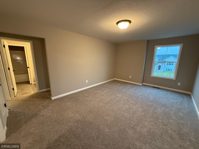 carpeted empty room featuring a textured ceiling