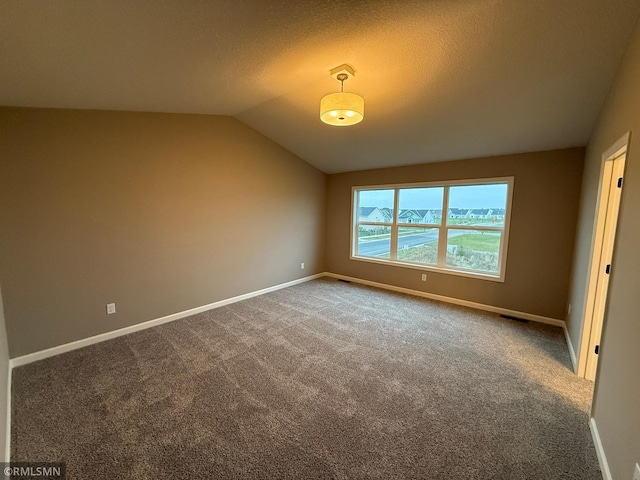 carpeted empty room featuring a textured ceiling and vaulted ceiling