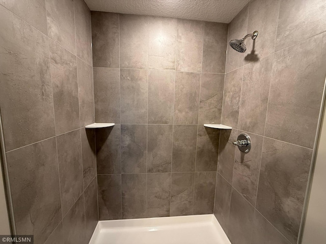 bathroom featuring a textured ceiling and tiled shower