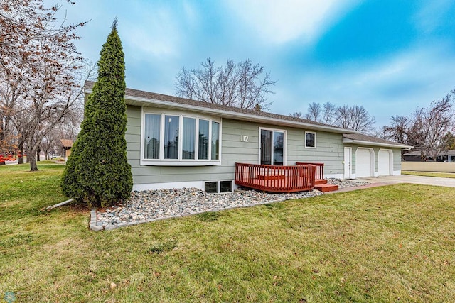 back of house featuring a garage, a yard, and a wooden deck