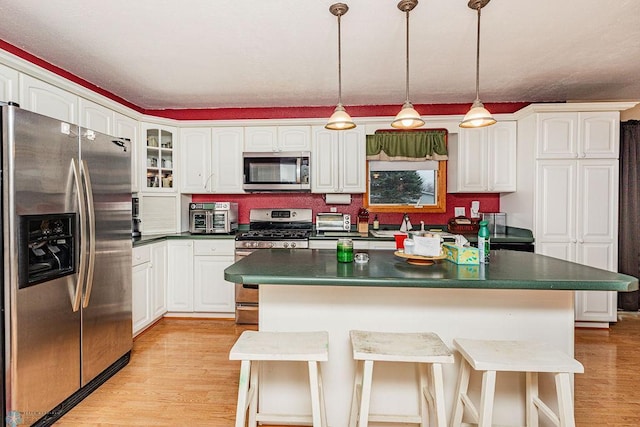 kitchen with light wood-type flooring, a breakfast bar, stainless steel appliances, white cabinetry, and a kitchen island