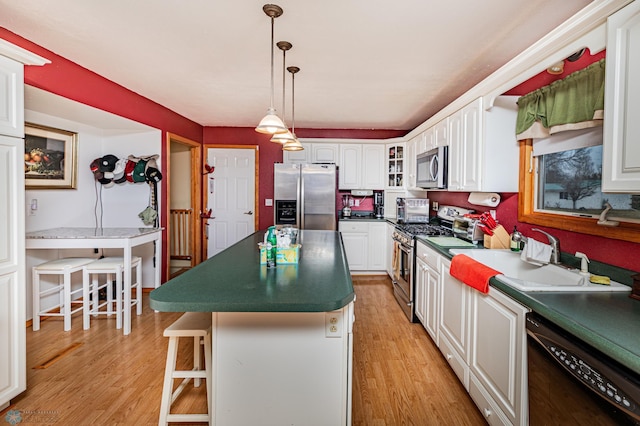 kitchen with white cabinetry, a center island, stainless steel appliances, light hardwood / wood-style floors, and a breakfast bar area