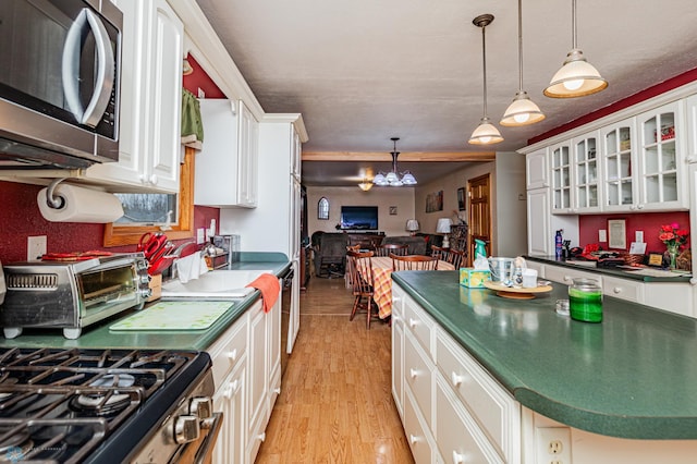 kitchen with hanging light fixtures, white cabinets, stainless steel appliances, and light hardwood / wood-style floors