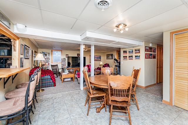 dining space with a paneled ceiling and light tile patterned flooring