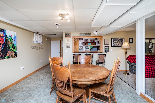 tiled dining space featuring a paneled ceiling