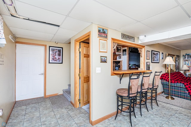 kitchen featuring a drop ceiling, a kitchen bar, and light tile patterned floors