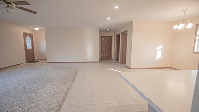 empty room with a healthy amount of sunlight, ceiling fan with notable chandelier, and light tile patterned floors