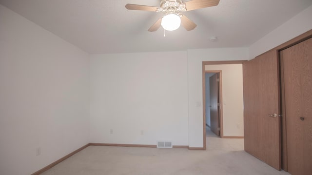 unfurnished bedroom with light colored carpet, ceiling fan, and a closet