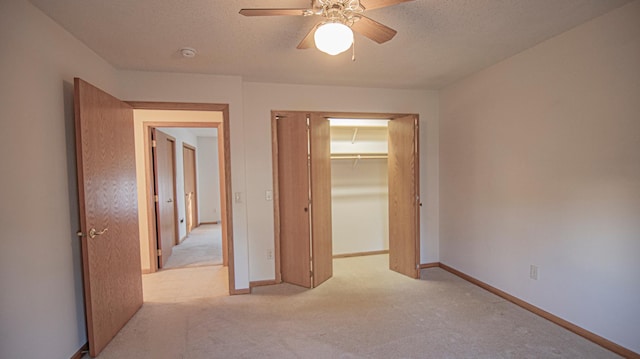 unfurnished bedroom with ceiling fan, light colored carpet, a closet, and a textured ceiling