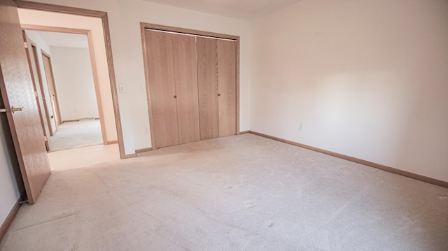 unfurnished bedroom featuring light carpet and a closet