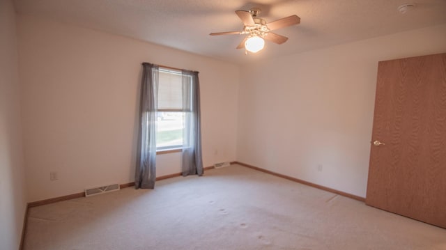 empty room with light colored carpet, a textured ceiling, and ceiling fan