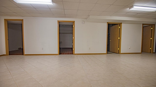 empty room featuring a drop ceiling and light tile patterned floors