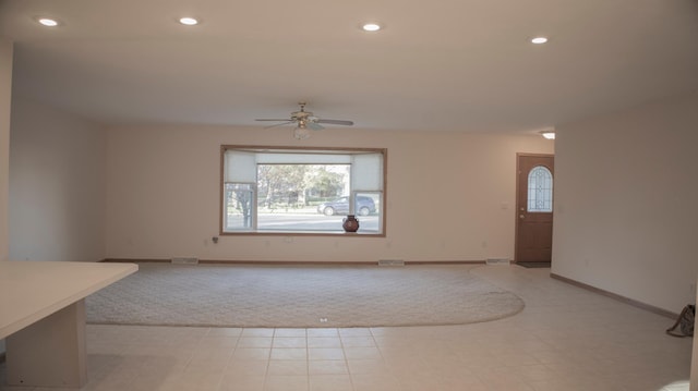 unfurnished living room featuring light colored carpet and ceiling fan