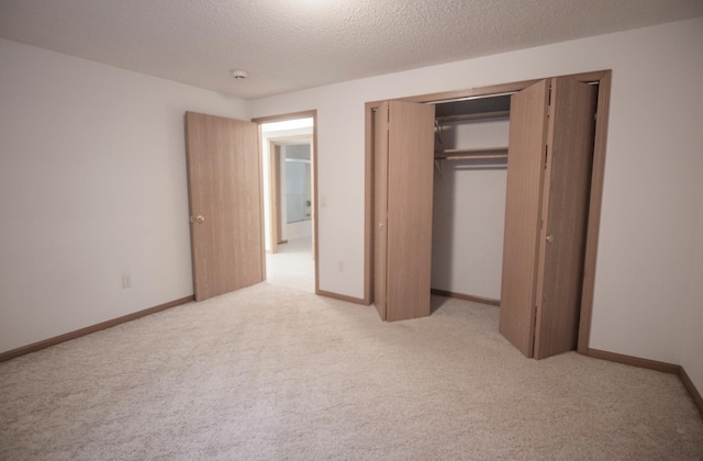 unfurnished bedroom with light carpet, a textured ceiling, and a closet