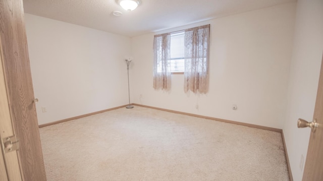 spare room with light carpet and a textured ceiling