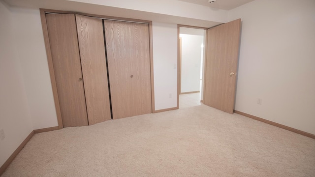 unfurnished bedroom with light carpet and a closet